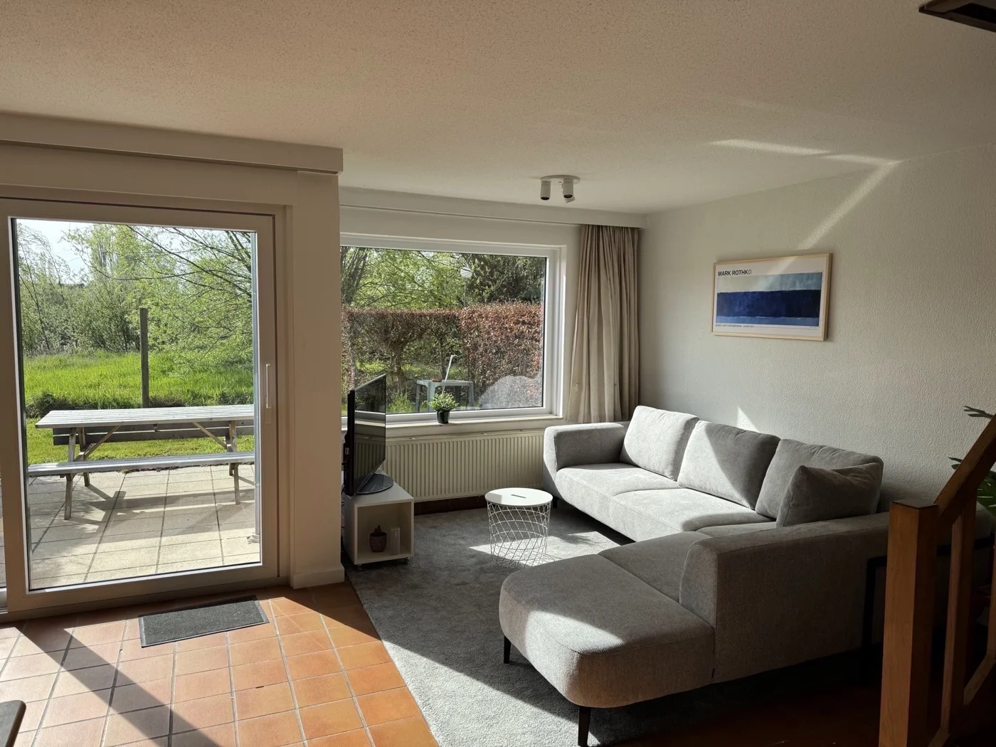 De living van vakantiehuis Condor16 in Nieuwpoort, met hoekbank en zicht op de tuin